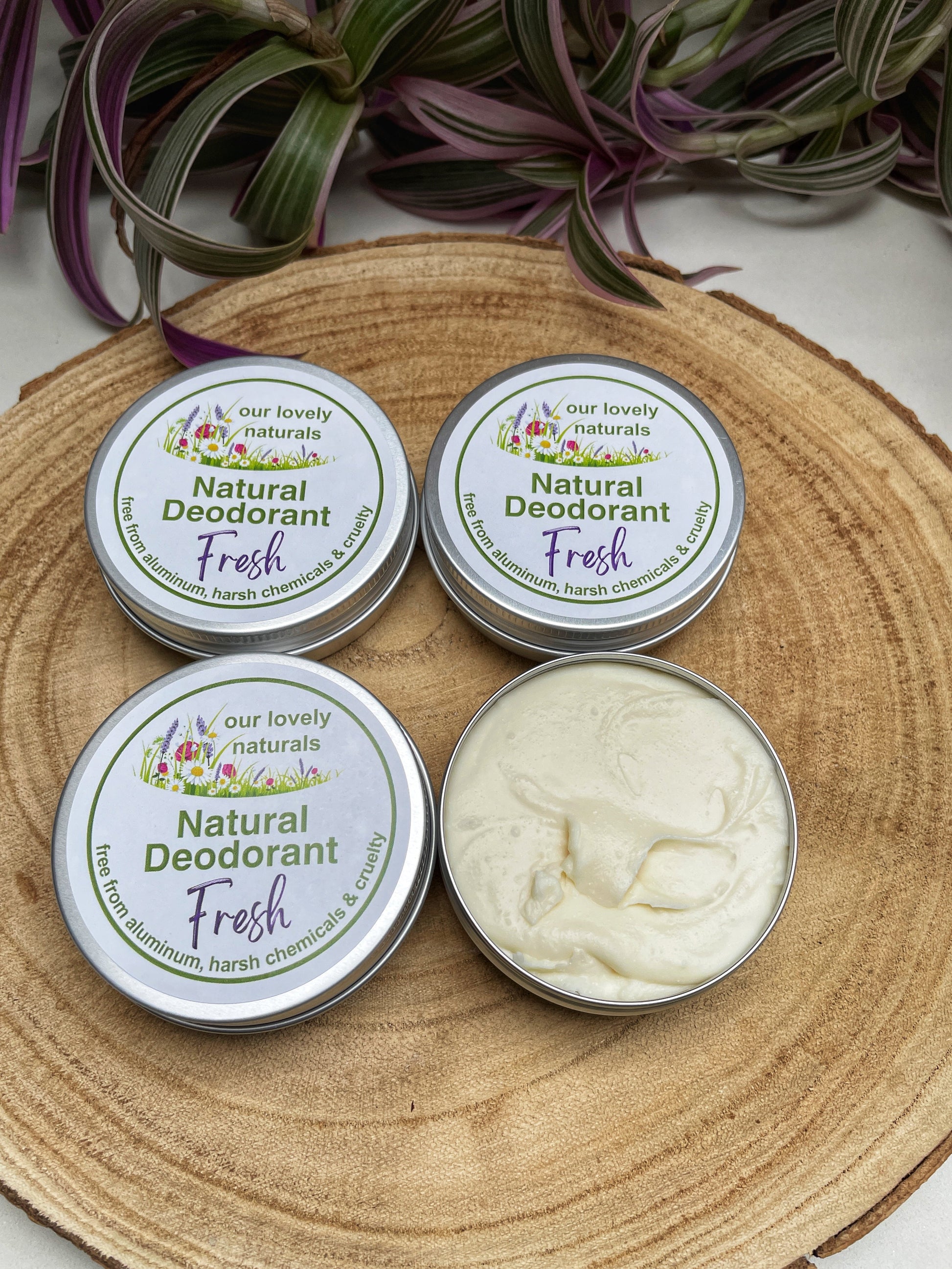 Four tins of handmade fresh natural deodorant on a wooden board