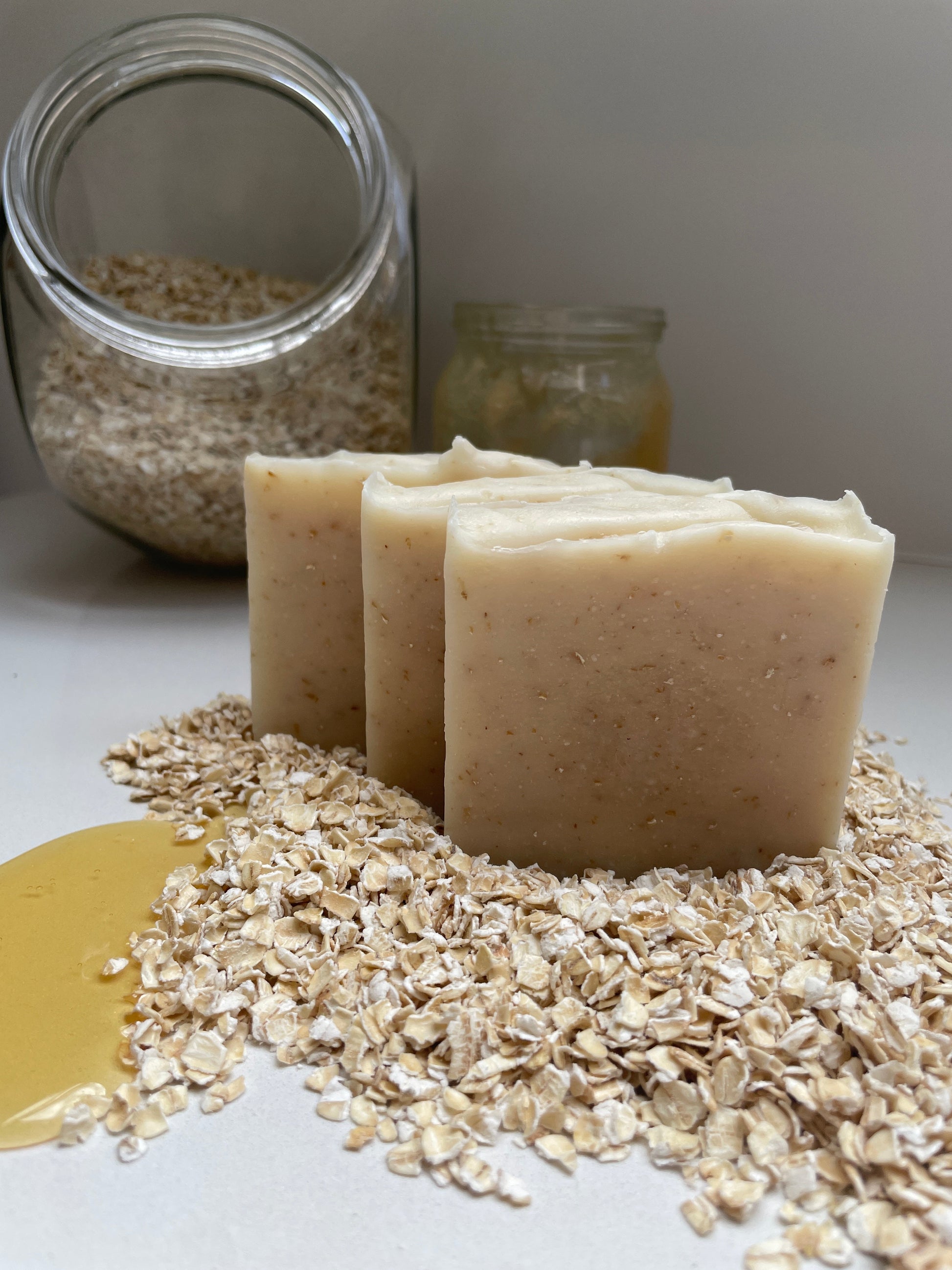 Environmentally friendly handmade natural honey & oat soap bars containing honey and oats.  Displayed with jars of honey and oats.