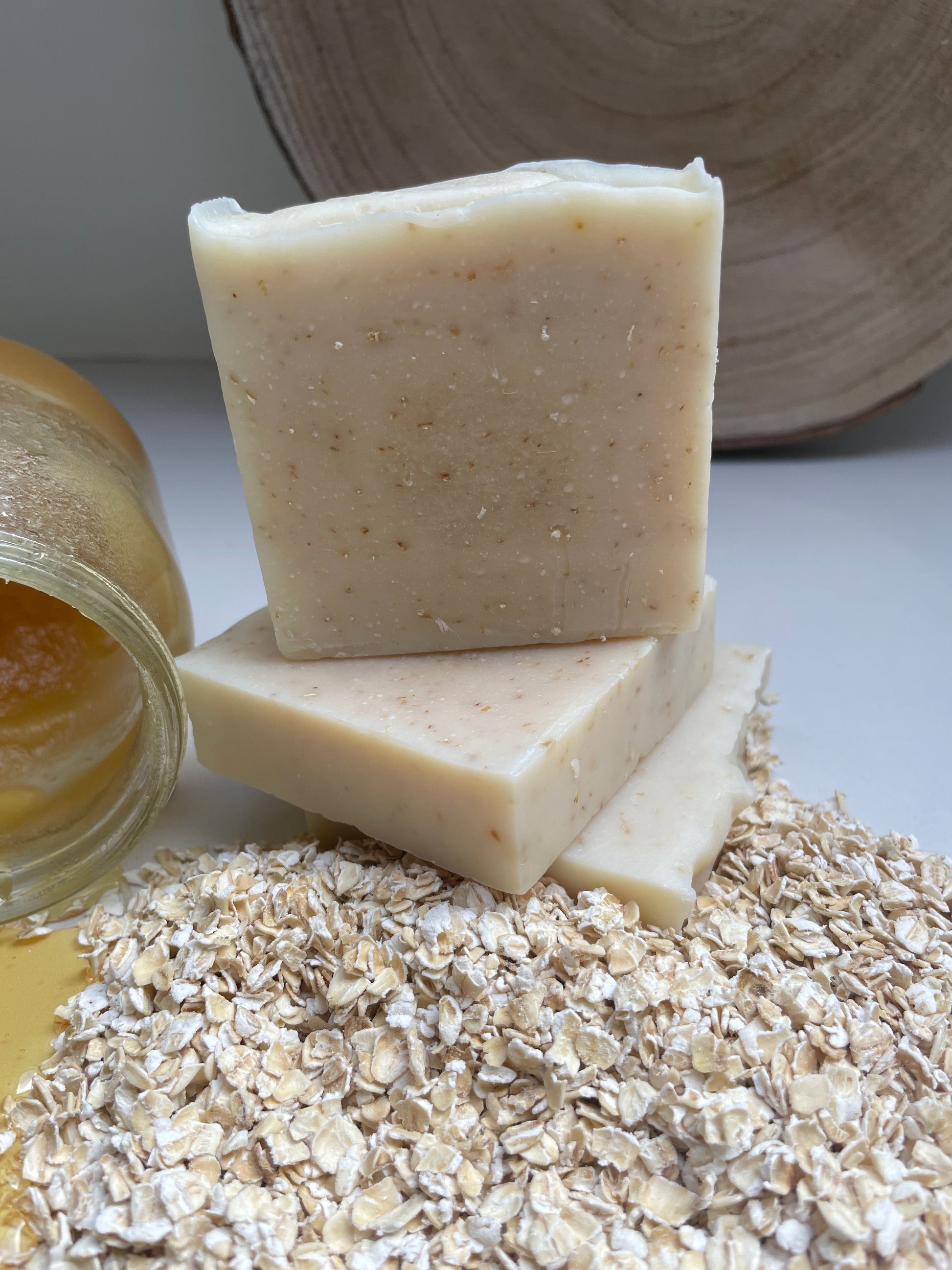 Environmentally friendly handmade natural honey & oat soap bars containing honey and oats.  Displayed with a jar of honey and loose oats.