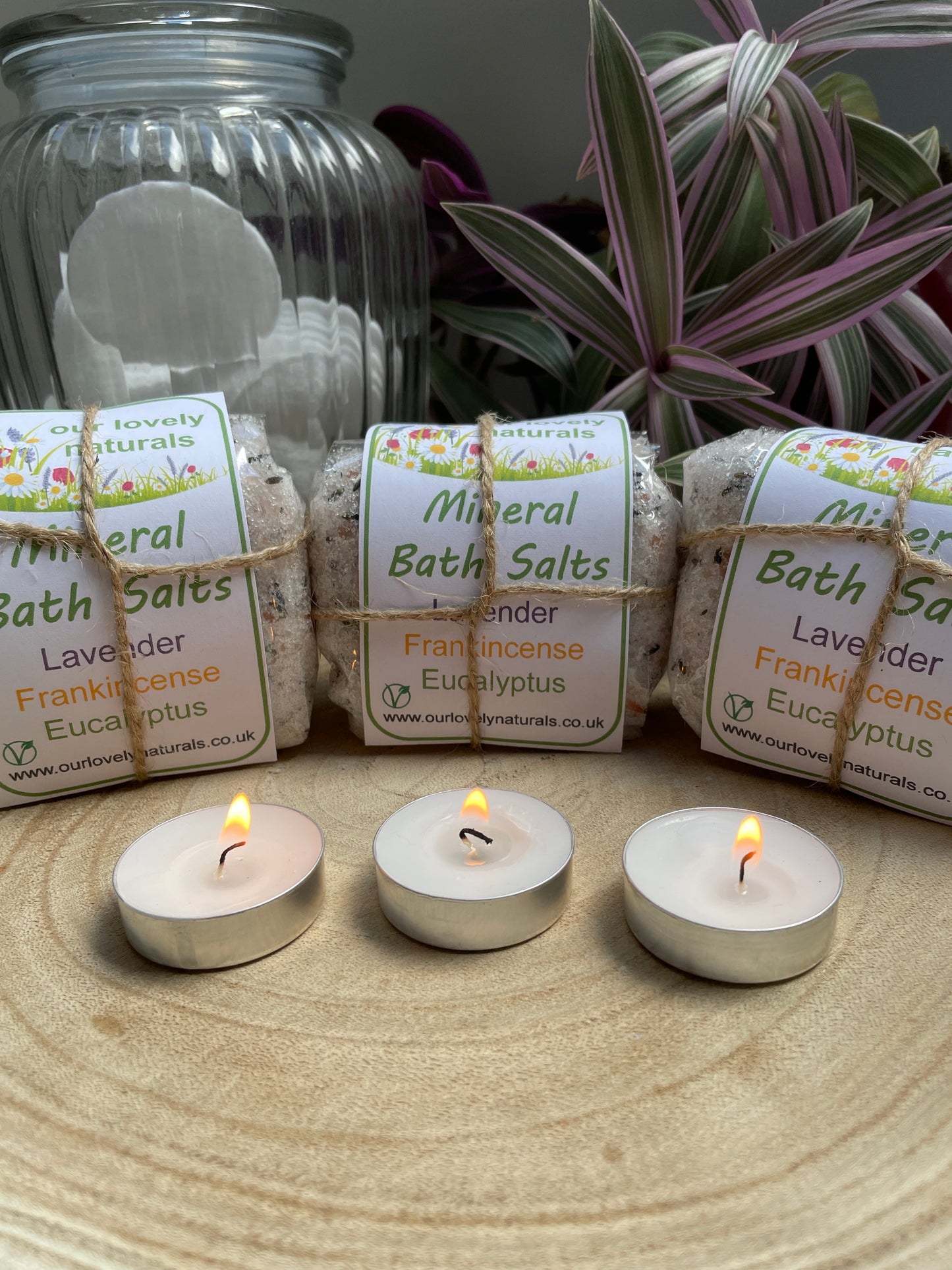 Lavender, Frankincense & Eucalyptus Mineral Bath Salts are completely natural and handmade, they are packaged in a biodegradable cellulose bag with label.  there is a plant, and some candles in the picture, they are all on a wooden board