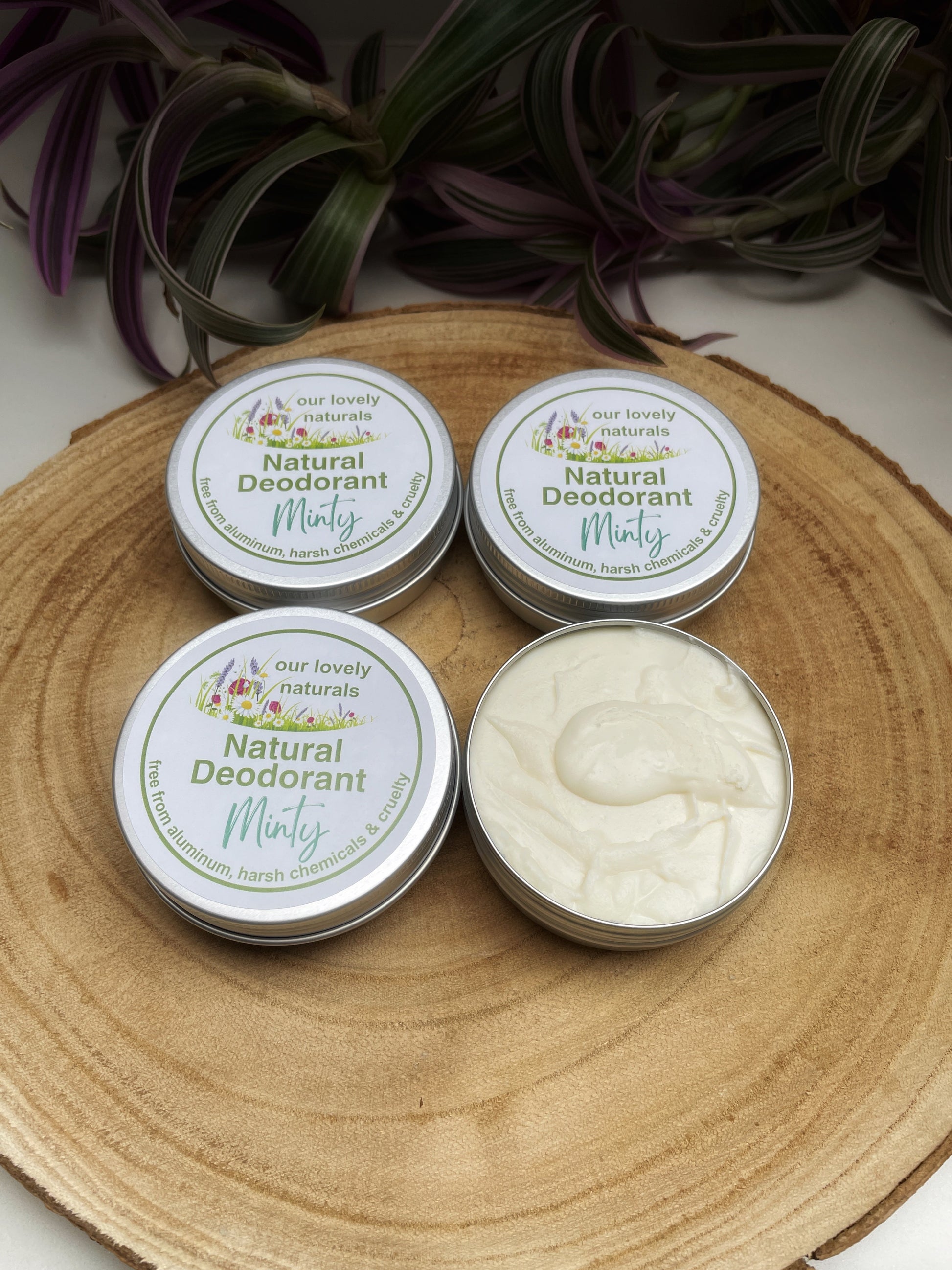 Four tins of handmade, sustainable, plastic free, minty natural deodorant on a wooden board