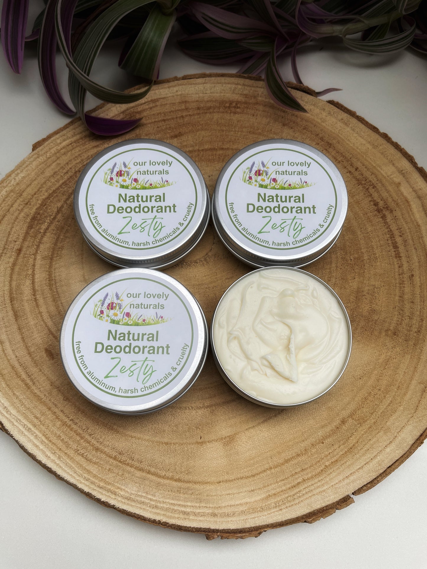 Four tins if handmade, sustainable, eco friendly, plastic free zesty natural deodorant on a wooden board