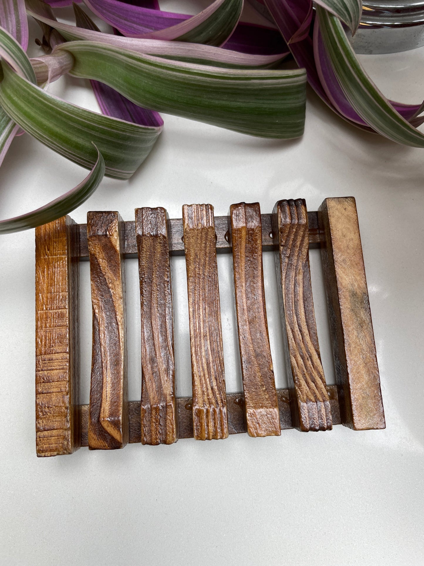 A wooden soap dish with a brown finish and a square slatted design.